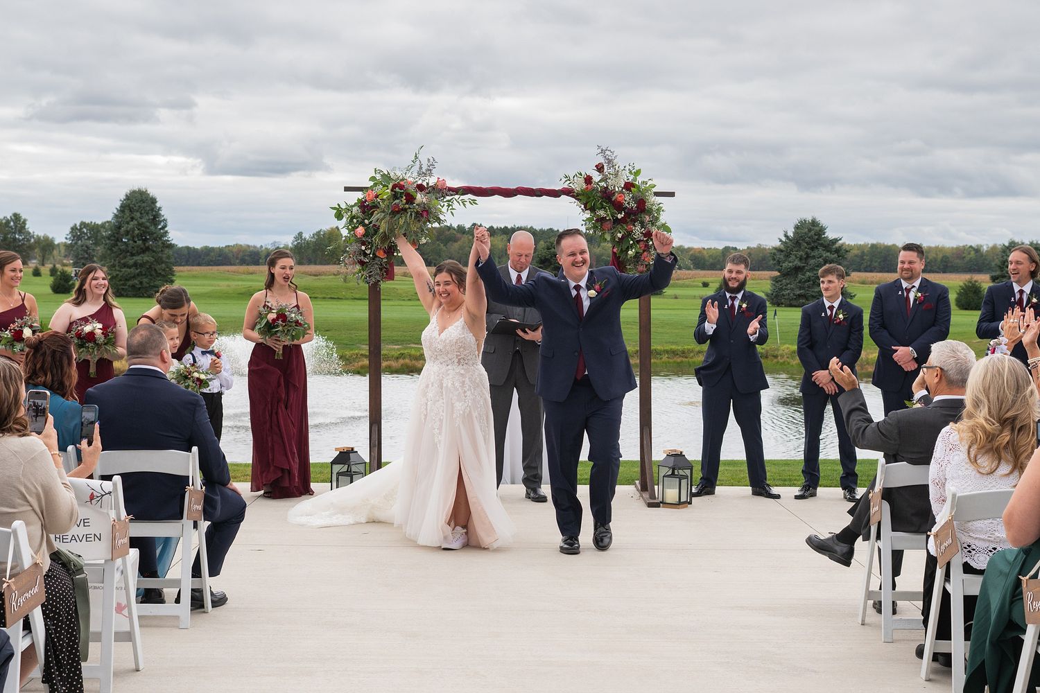 Joyful newlyweds celebrate as they walk back down the aisle after their outdoor wedding ceremony with cheering guests.