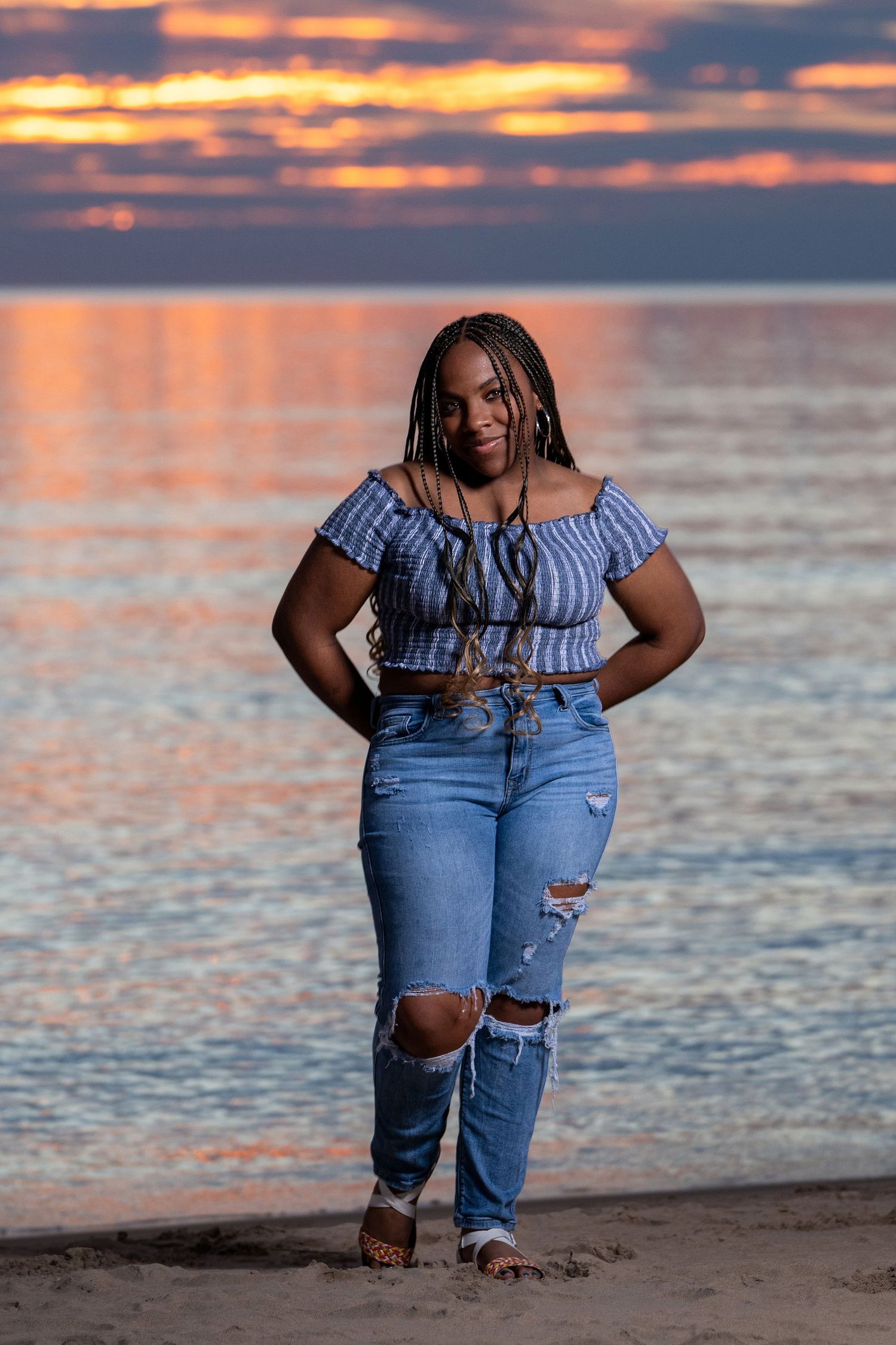 A beach photoshoot at sunset with dramatic orange sky and ocean backdrop.