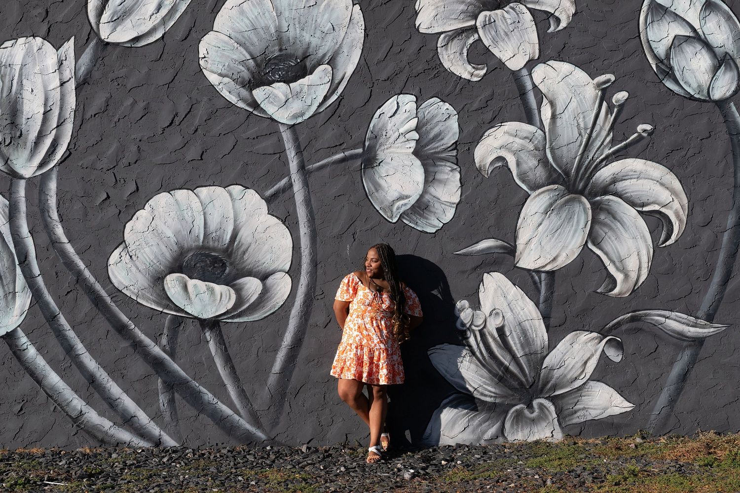 Black and white floral mural serves as backdrop for creative portrait photography.