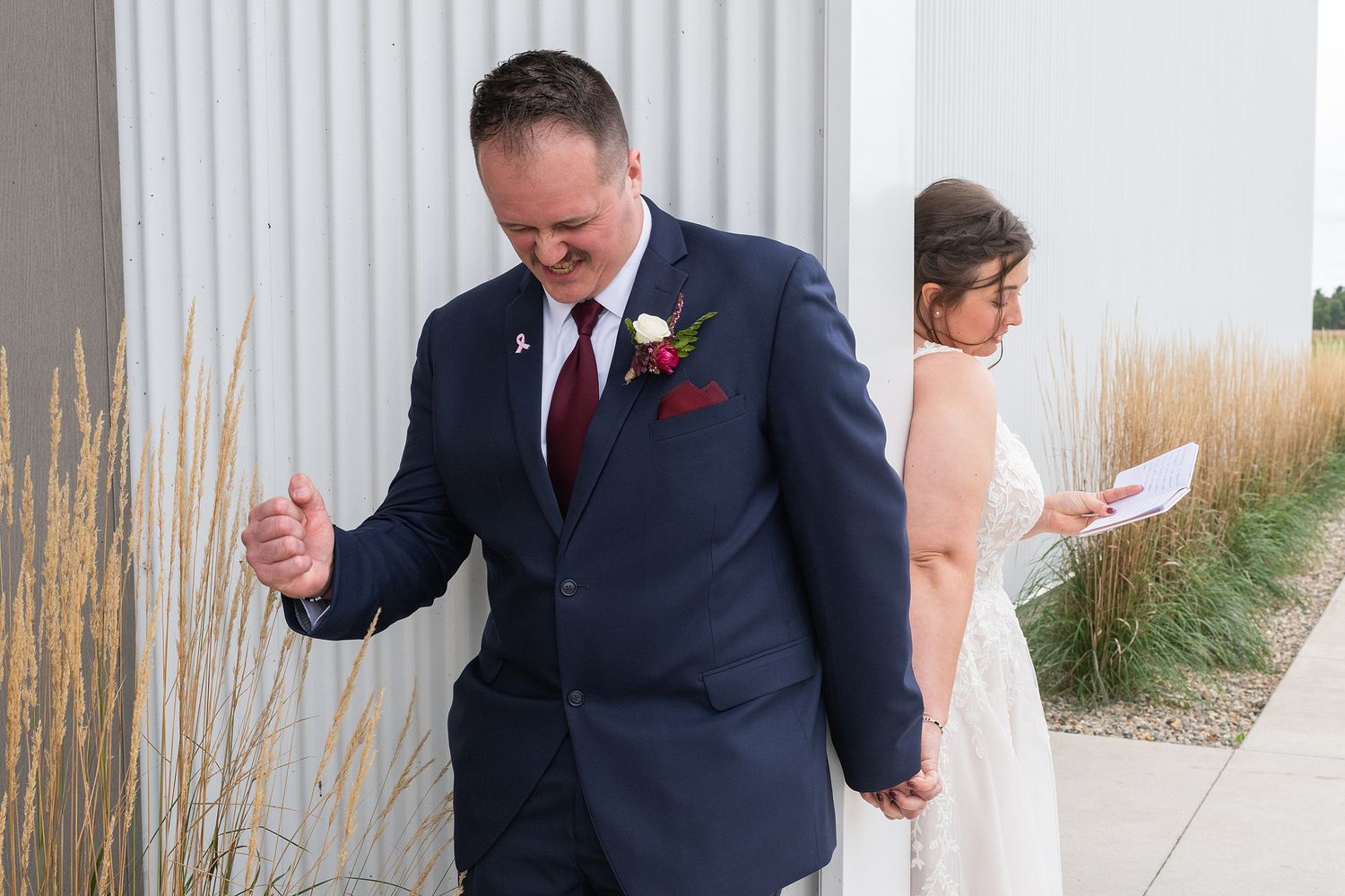 Groom in navy suit reacting emotionally during first look with bride.