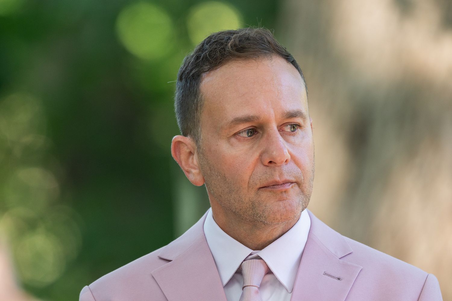 A collage of five outdoor portrait photos showing someone wearing a light-colored suit against blurred natural backgrounds.