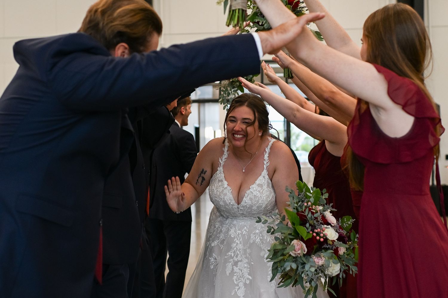Bride walks through high-five tunnel of wedding party guests at ceremony.