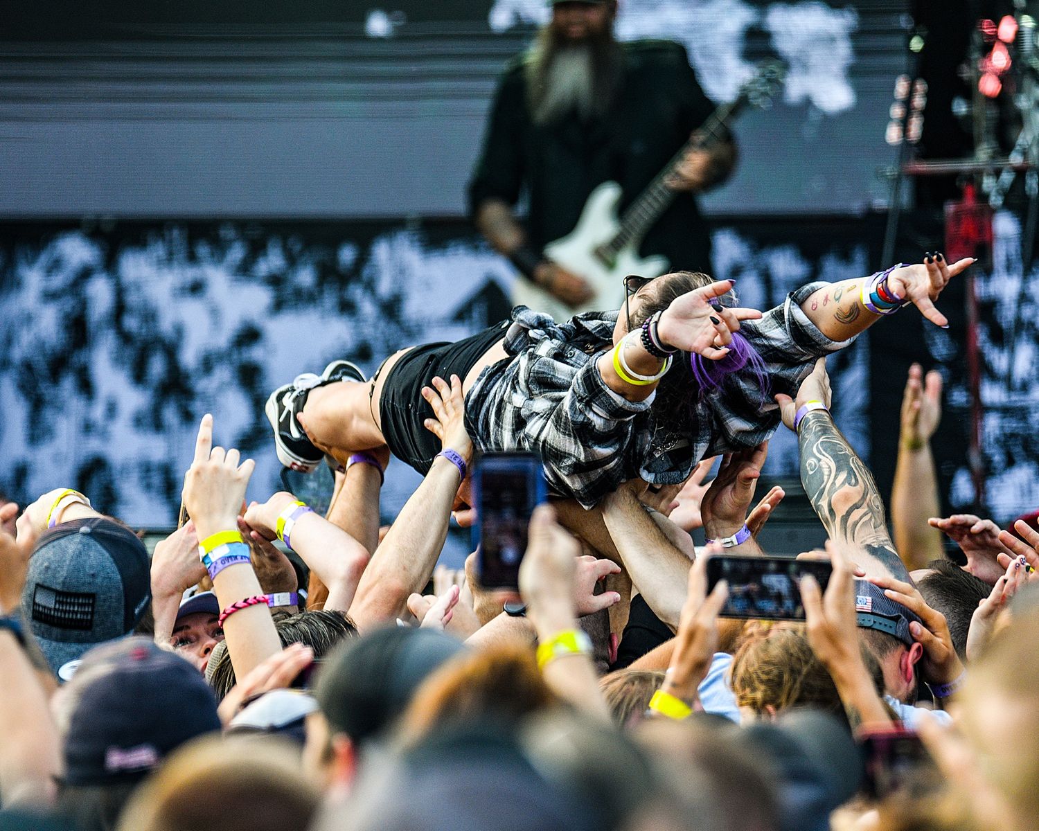 Concert crowd holds up phones with flashlights during live music performance.