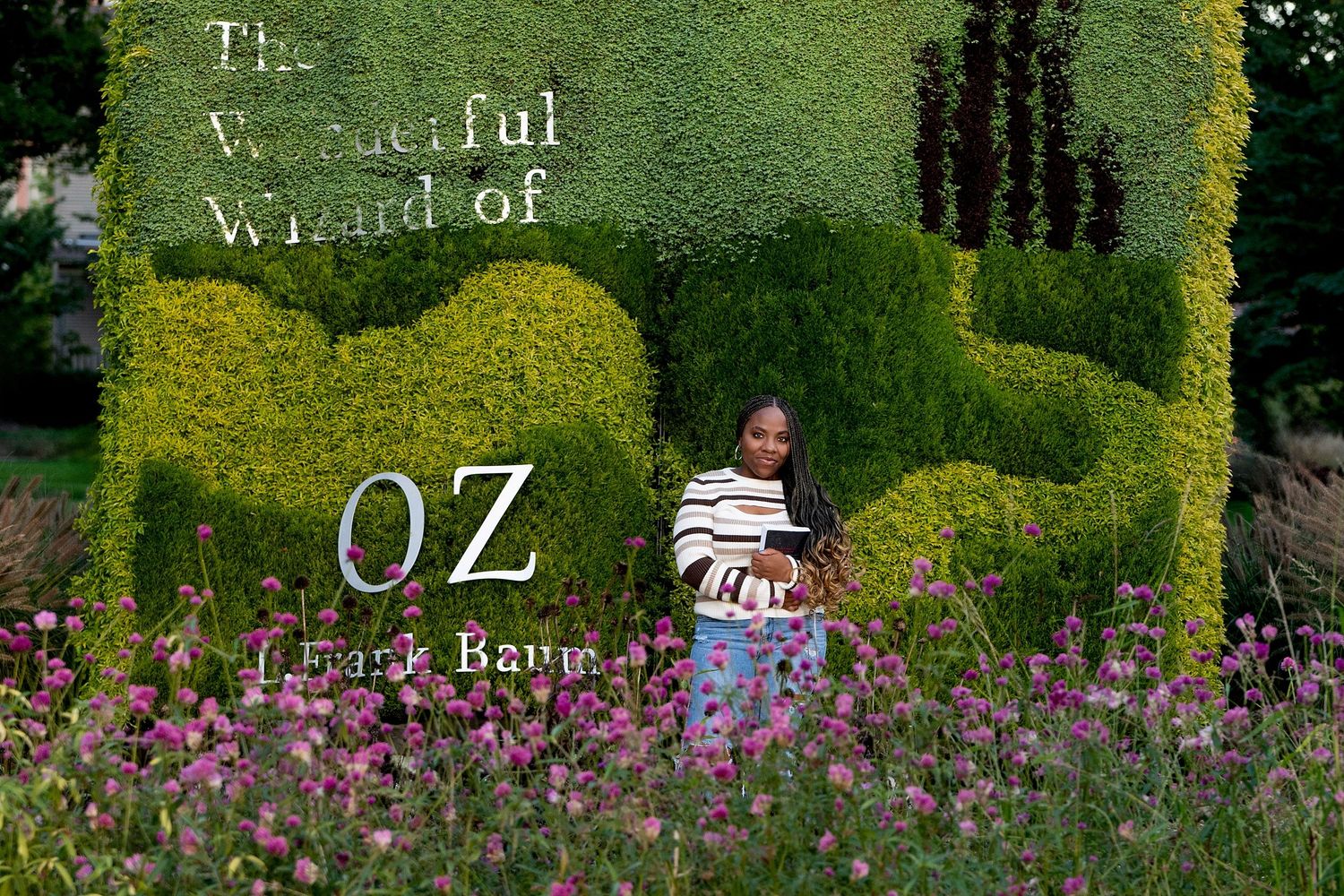 A garden portrait setting with lush green hedges and purple flowers.