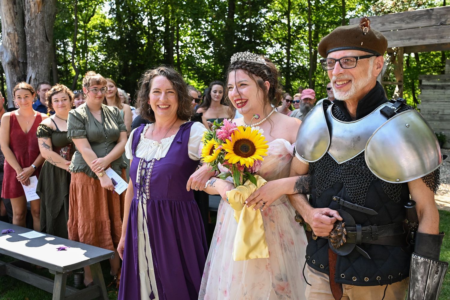 Wedding party and guests celebrating with sunflowers in an outdoor garden setting.