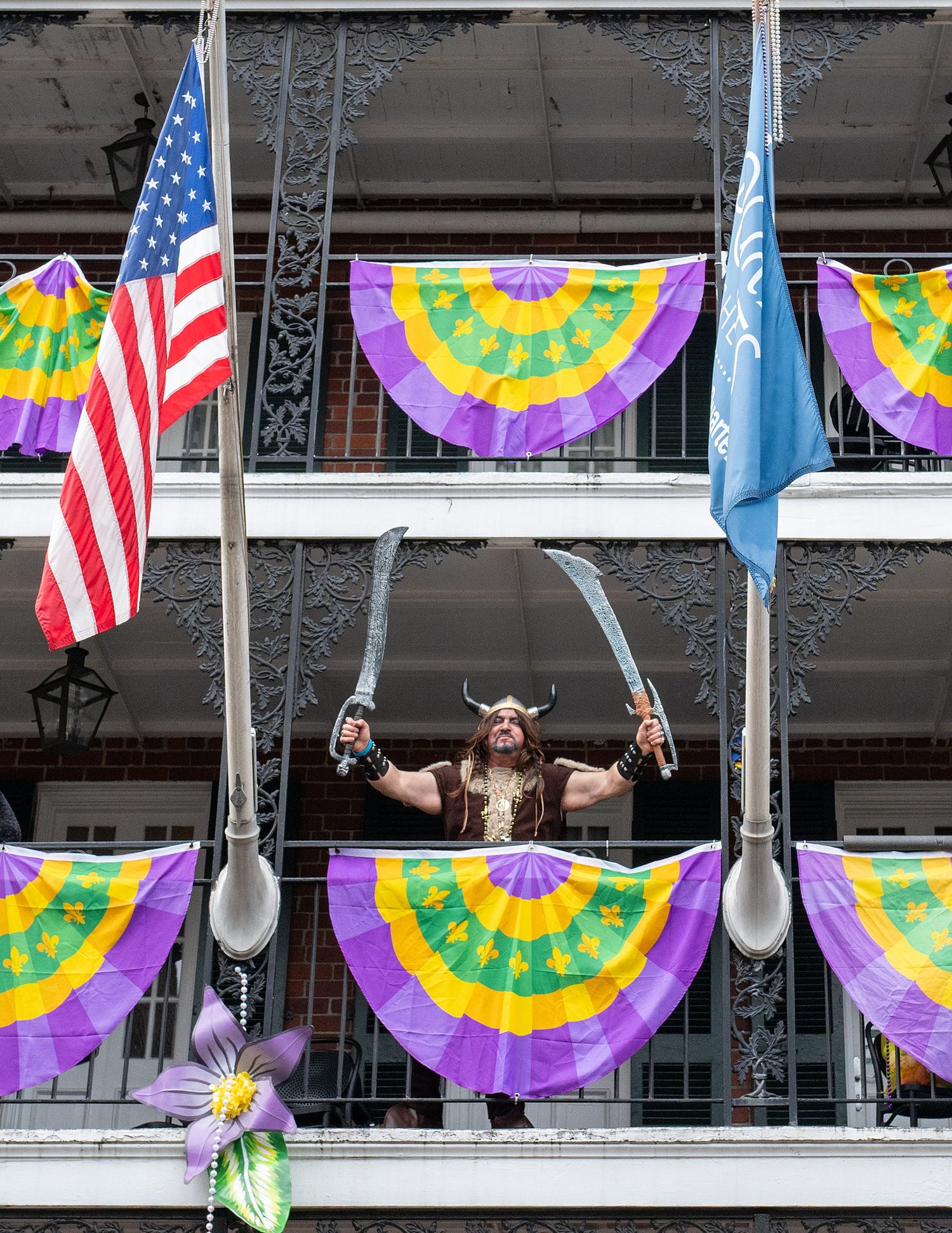 Person in viking costume stands on balcony with American flag and colorful bunting decorations.