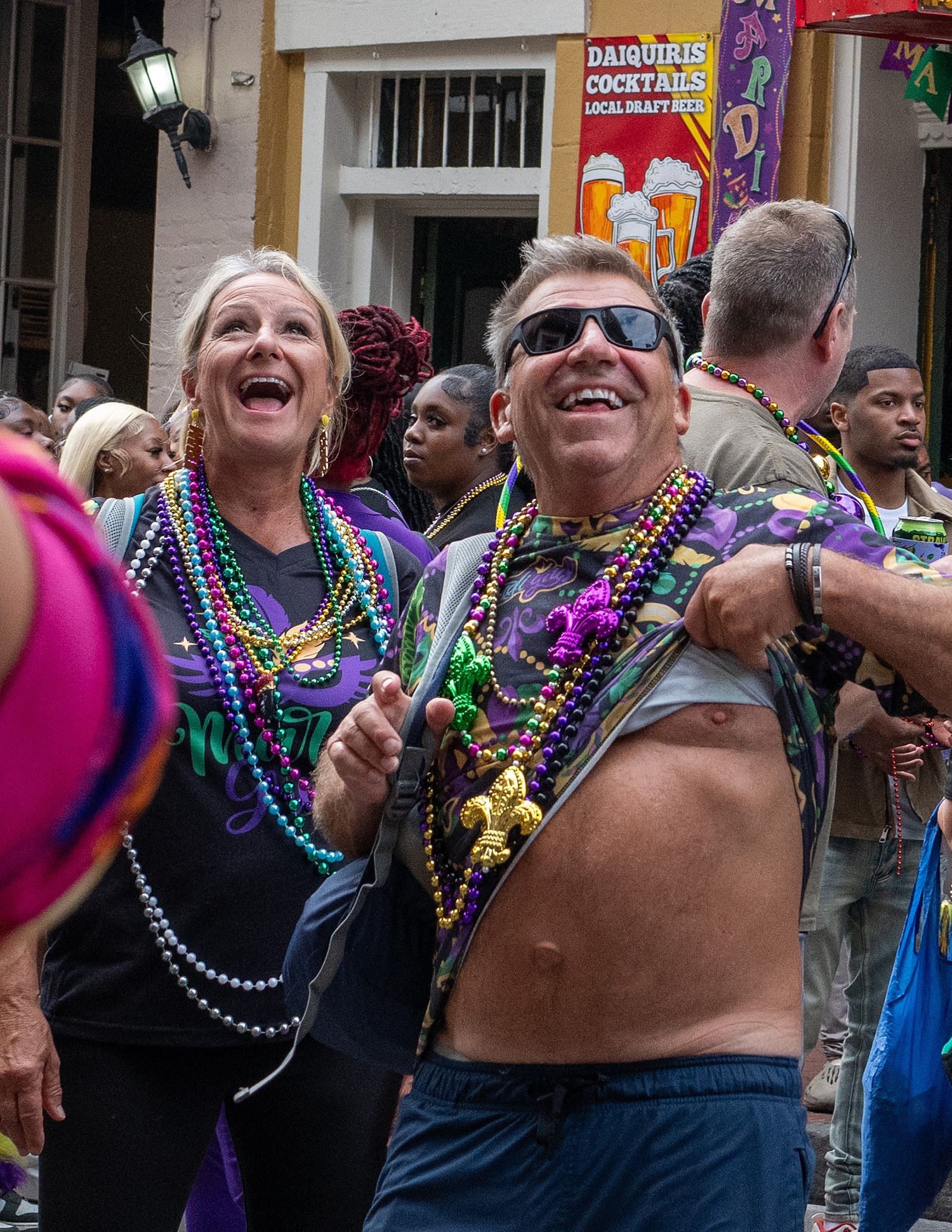 Revelers wearing Mardi Gras beads celebrate on Bourbon Street during carnival season.