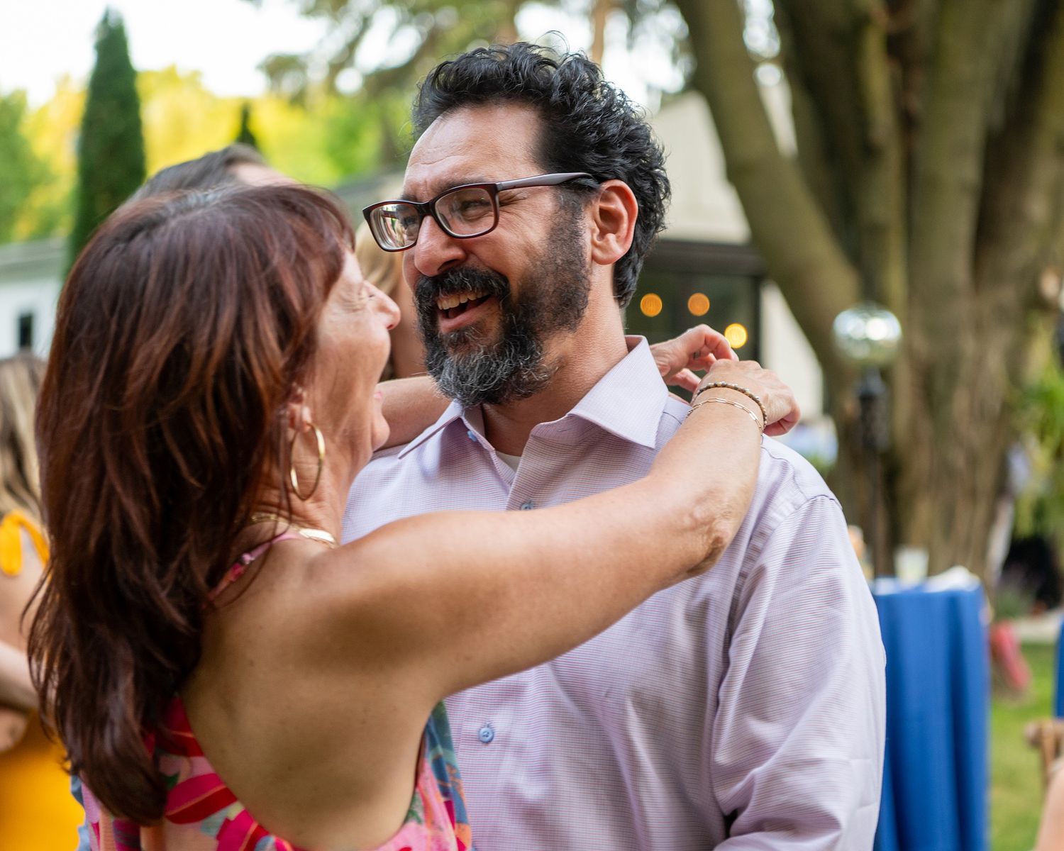 A romantic couple shares a tender moment outdoors in a garden setting with trees in the background.