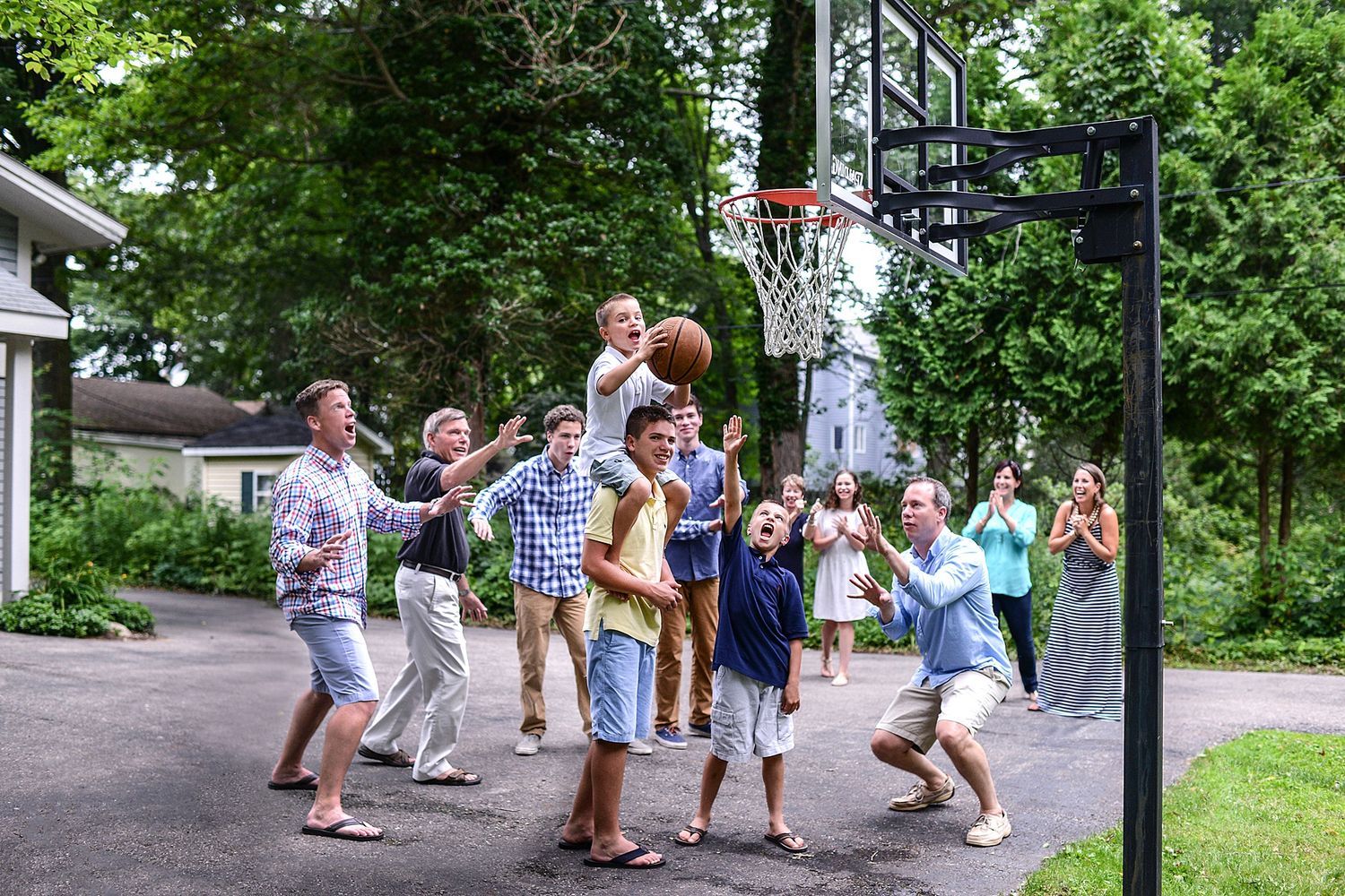 Group of people playing and interacting on a tree-lined pathway during summer.