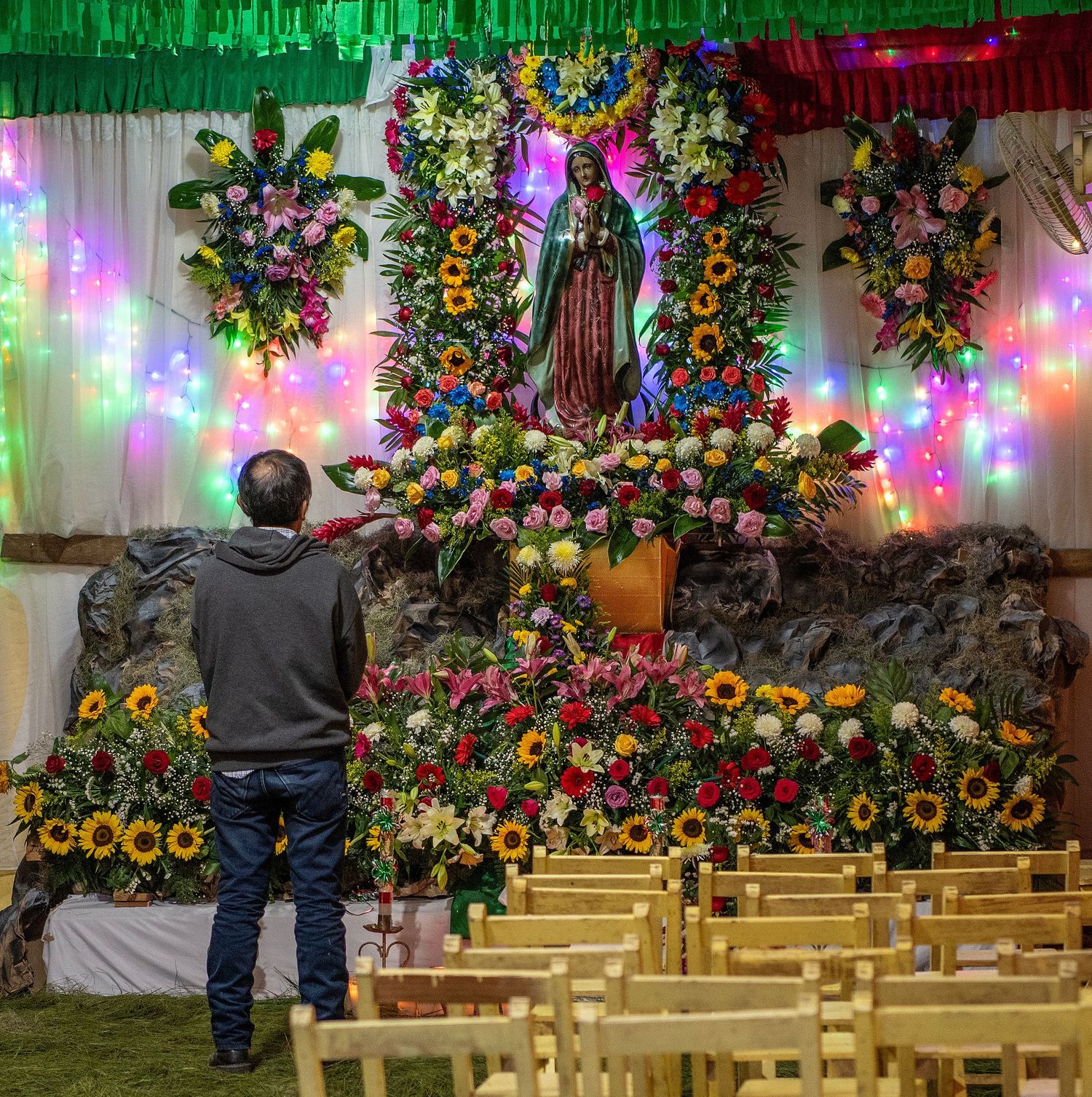 Colorful floral arrangements and wooden benches decorate an indoor venue with festive lighting.