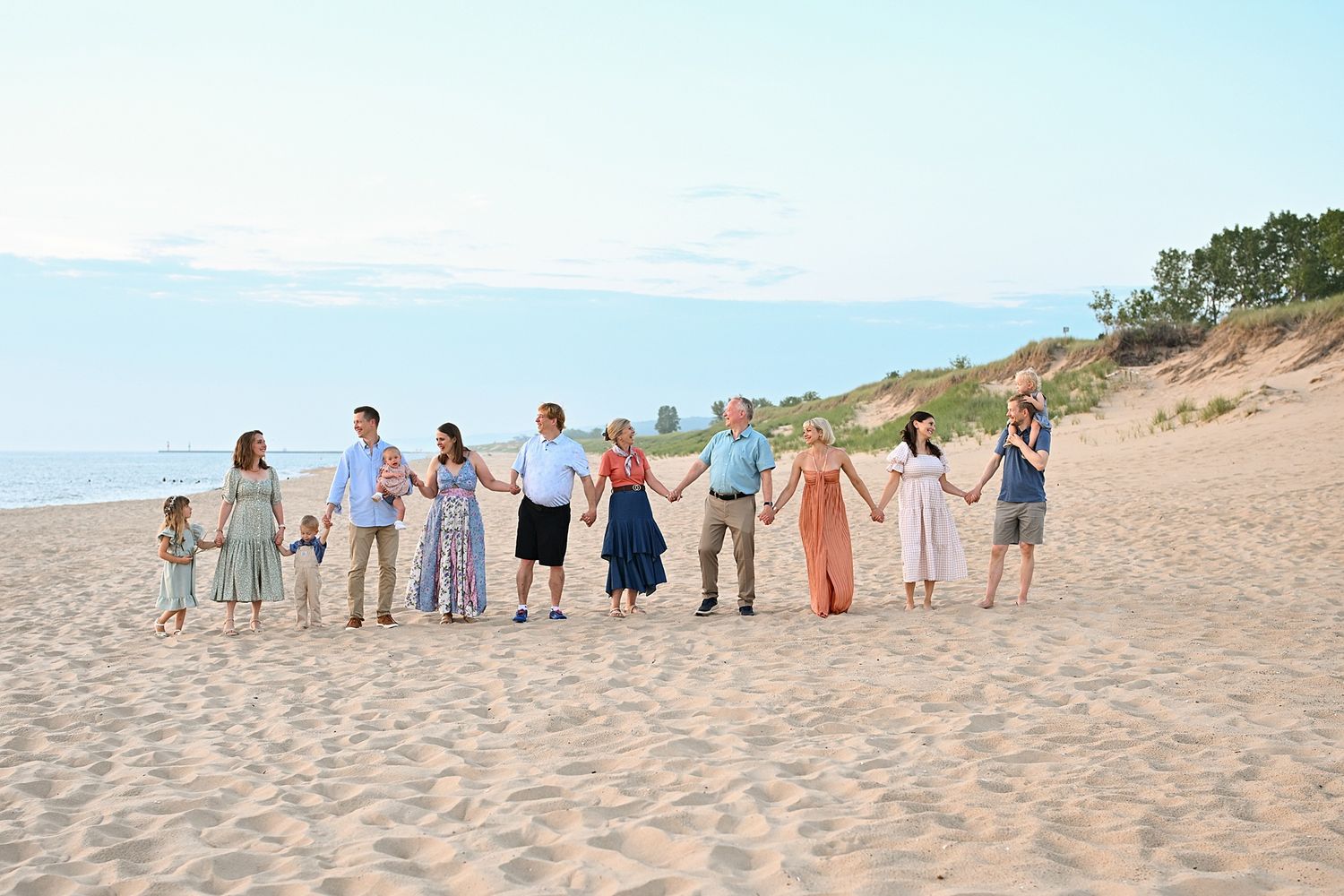 Family members arranged in a line for photos on a sandy beach at sunset.