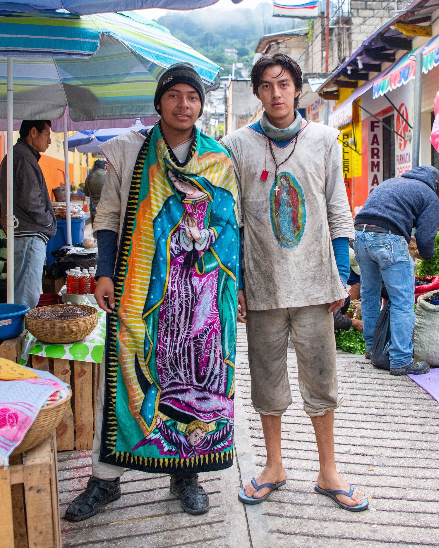 Market vendors wearing traditional colorful clothing and scarves in outdoor marketplace.