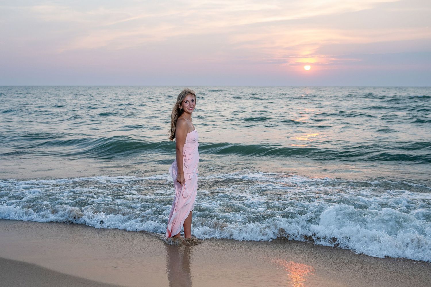 Sunset beach scene with waves crashing on shore during golden hour.