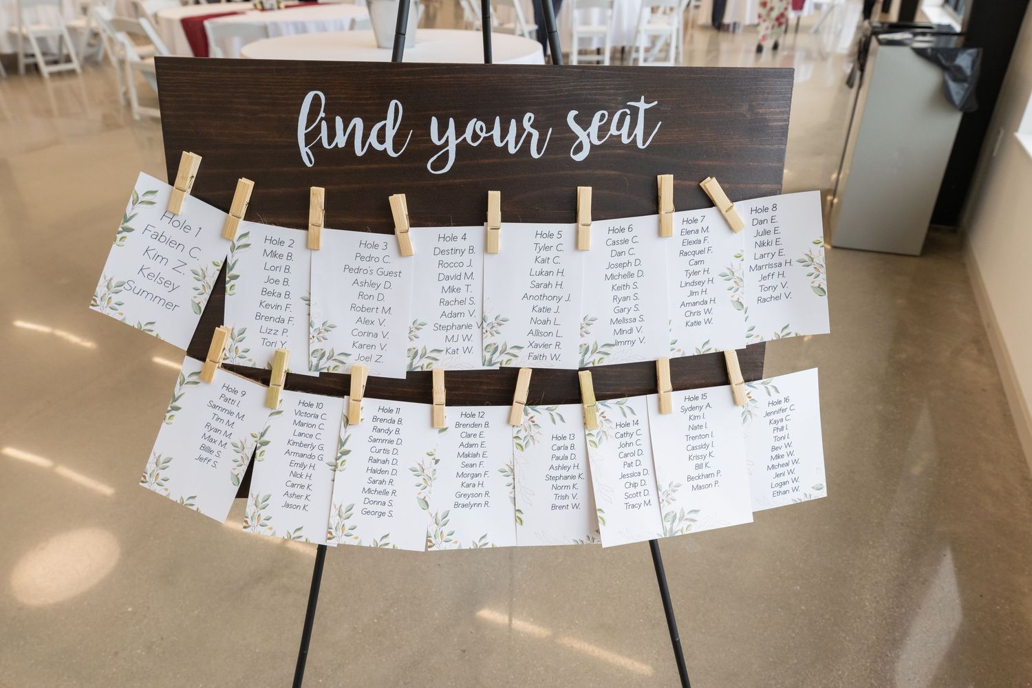 Rustic wedding seating chart sign with clothespin cards reading find your seat on dark wood.