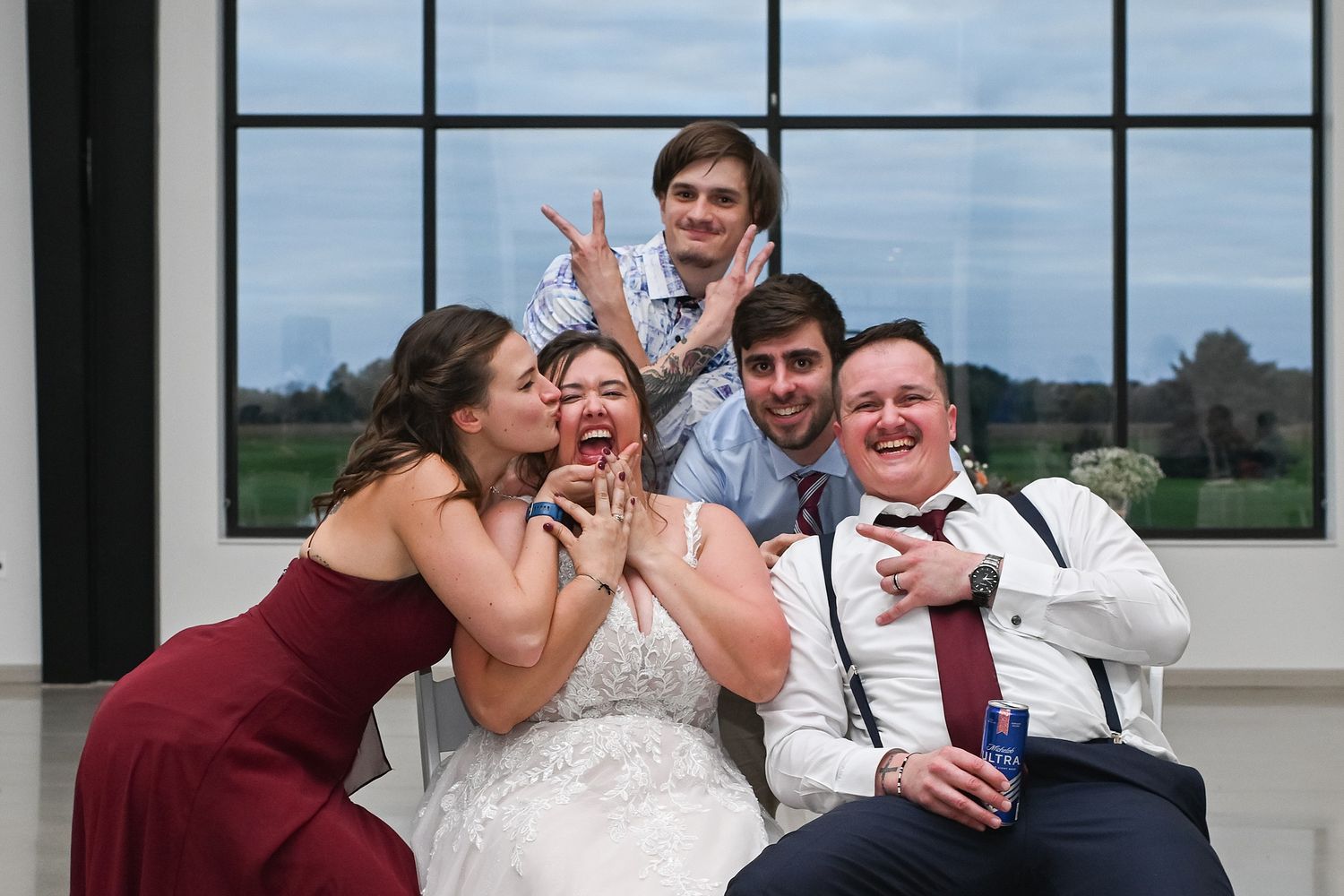 Bride and groom celebrate with friends posing for fun wedding reception photo indoors.