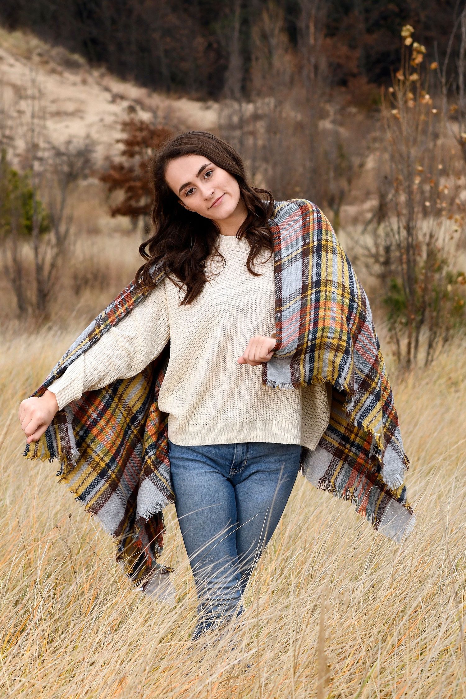 Autumn fashion portrait featuring cozy sweater and plaid blanket scarf in tall grass.