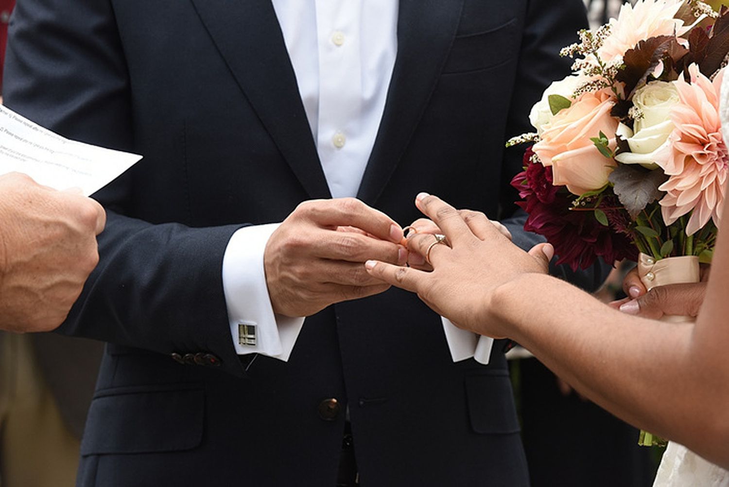 Close-up of hands exchanging rings during an elegant wedding ceremony.