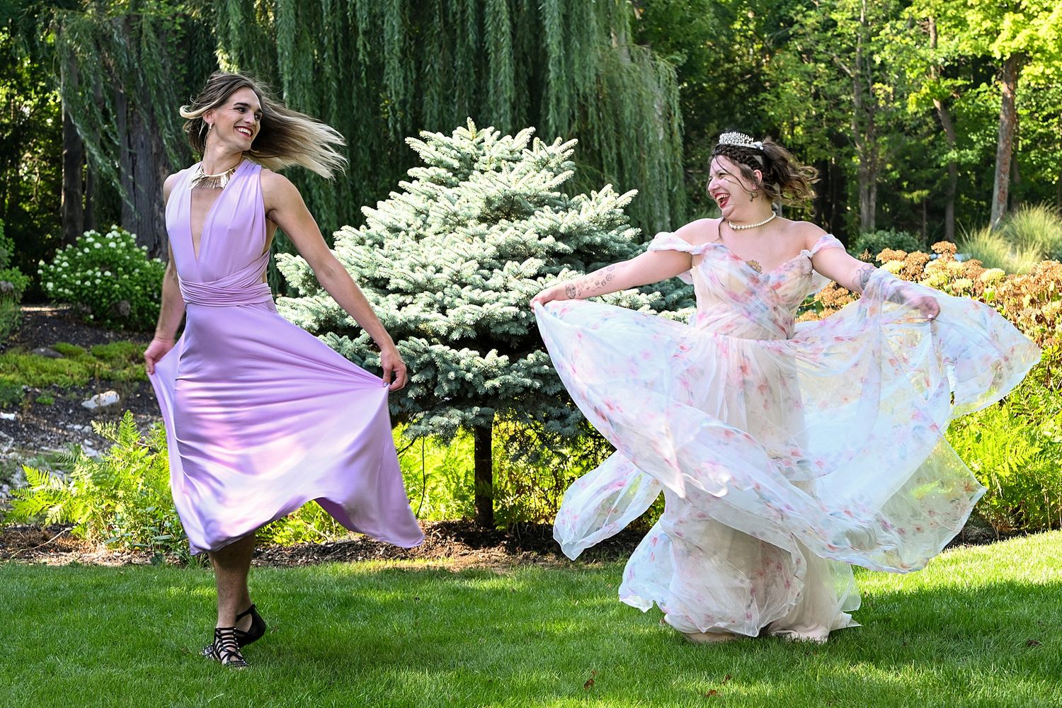 Women in purple dresses twirling and dancing in a sunny garden setting.