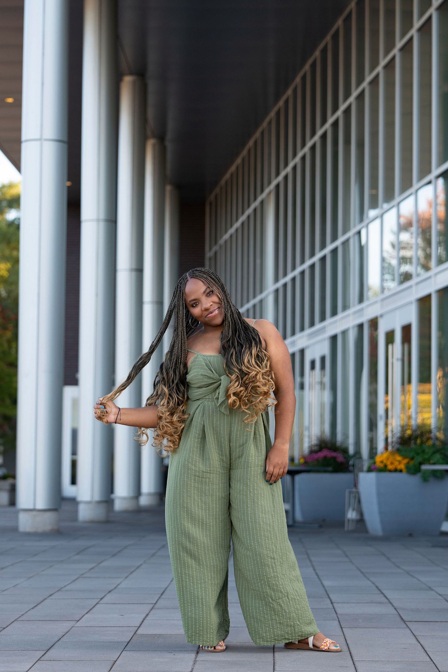 Modern architectural photoshoot with white columns and green jumpsuit.