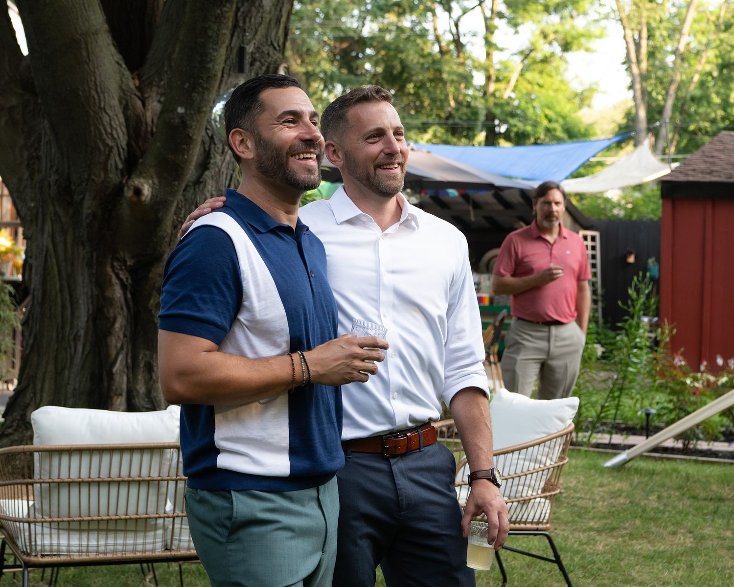 People enjoying an outdoor gathering in a backyard garden setting with patio furniture and natural lighting.