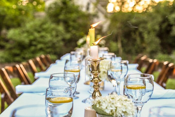 Elegant outdoor wedding reception tables decorated with white flowers and glassware at sunset.