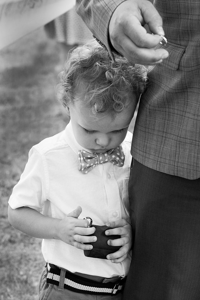 Black and white photo of a young child adjusting formal attire.