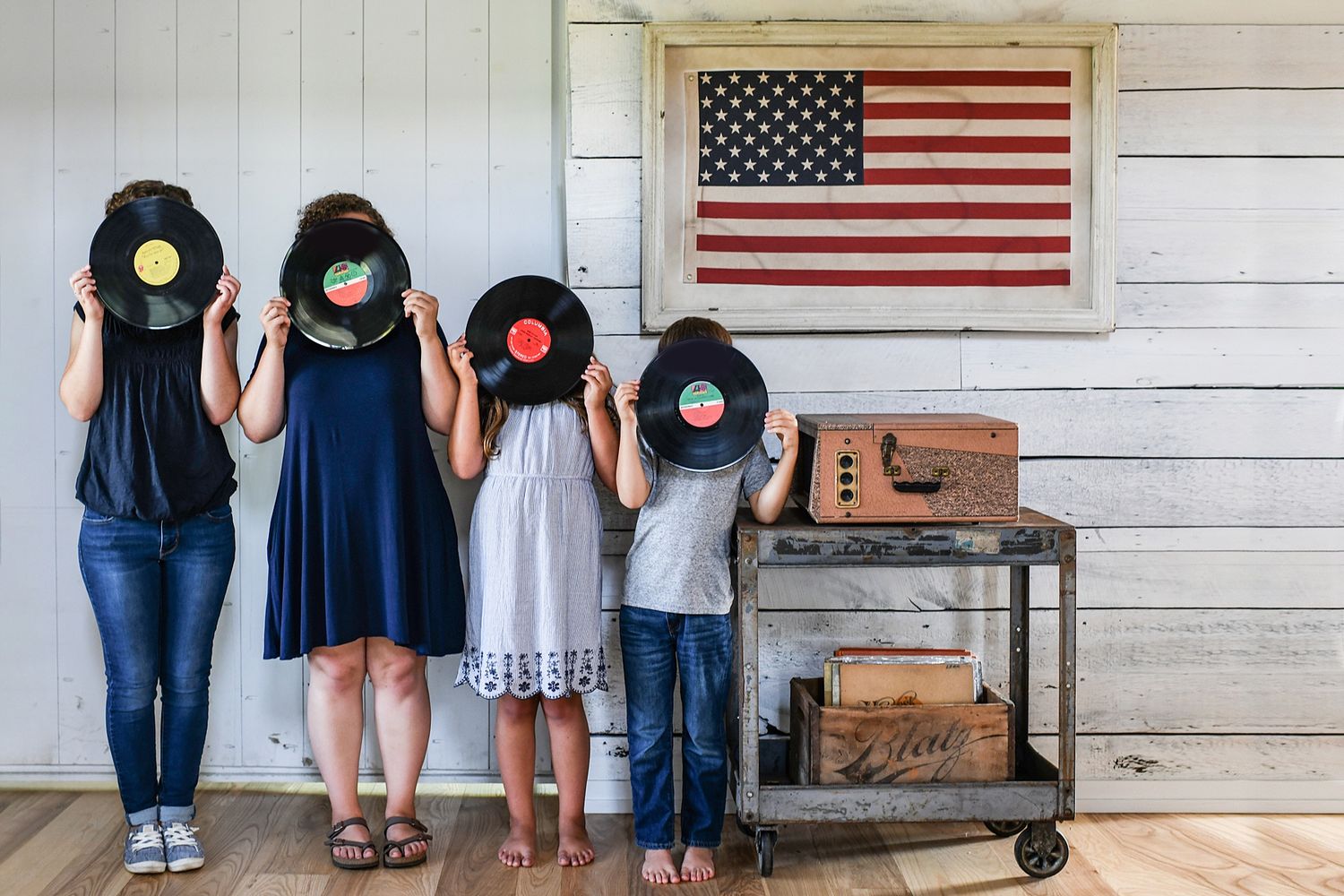 Creative family portrait with vintage records against white wall with American flag decor.
