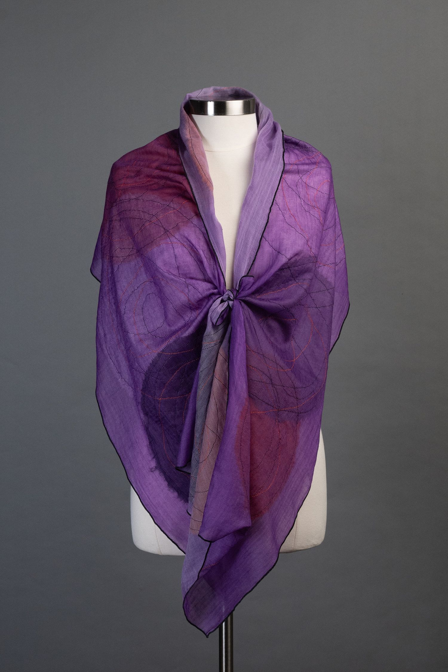 Purple sheer silk scarf displayed on mannequin against grey background.