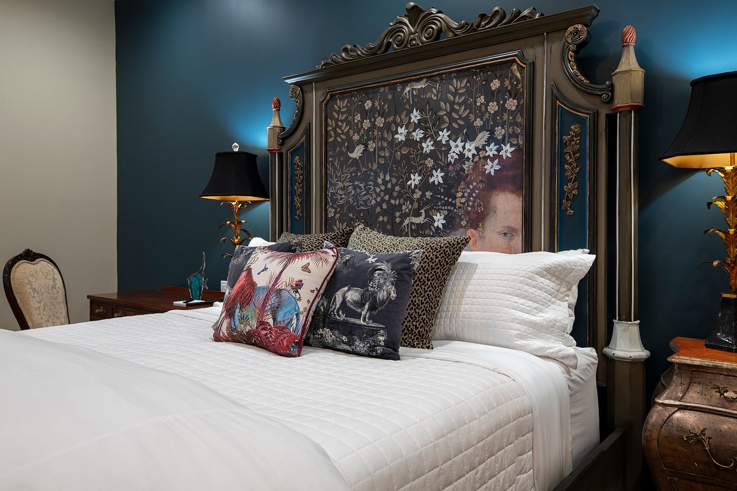 Dark blue bedroom with ornate gold frame headboard and dramatic lighting.