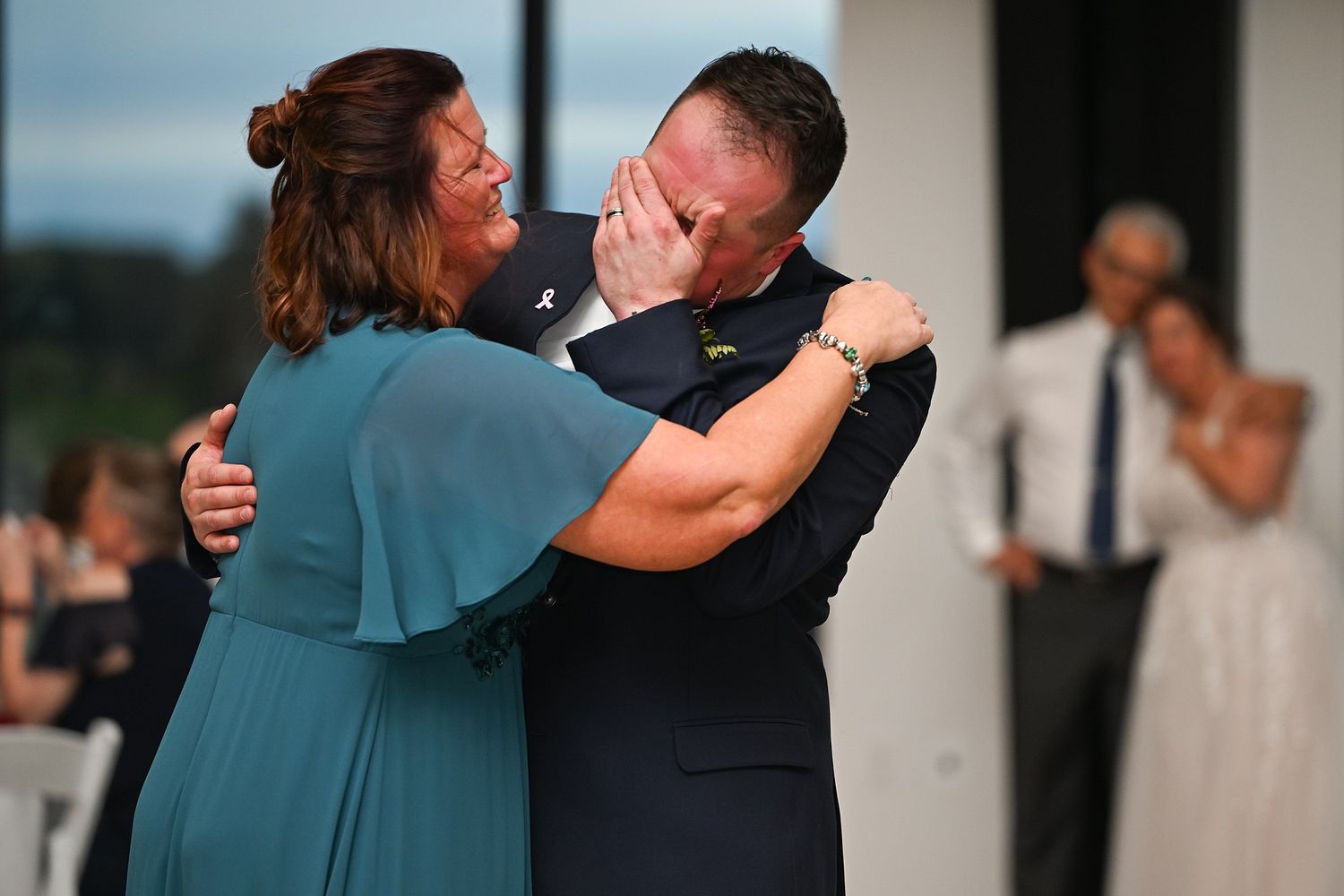Emotional mother and son sharing a heartfelt dance embrace during wedding reception celebration.