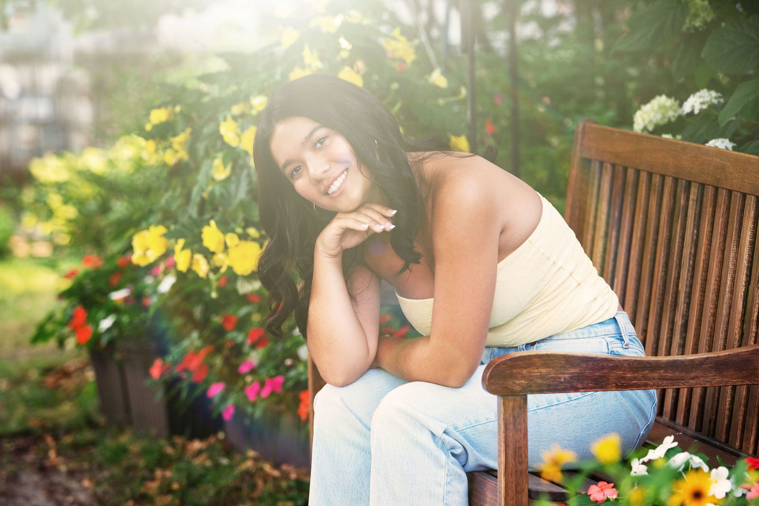 Peaceful garden scene with wooden bench surrounded by blooming yellow and red flowers.