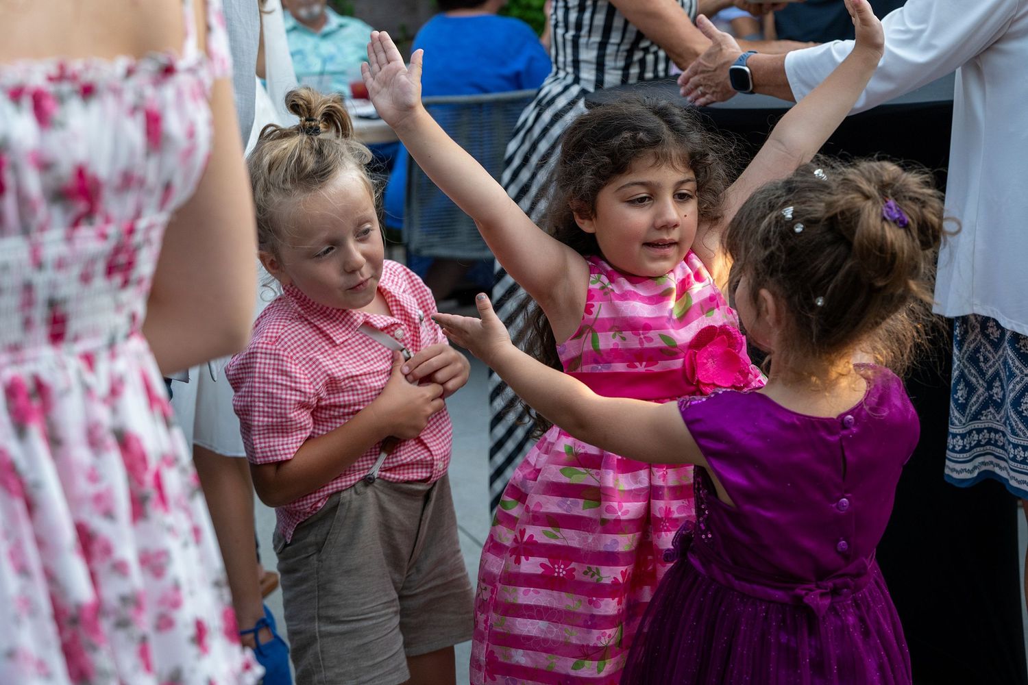 Children dancing and playing at a wedding reception in colorful outfits.