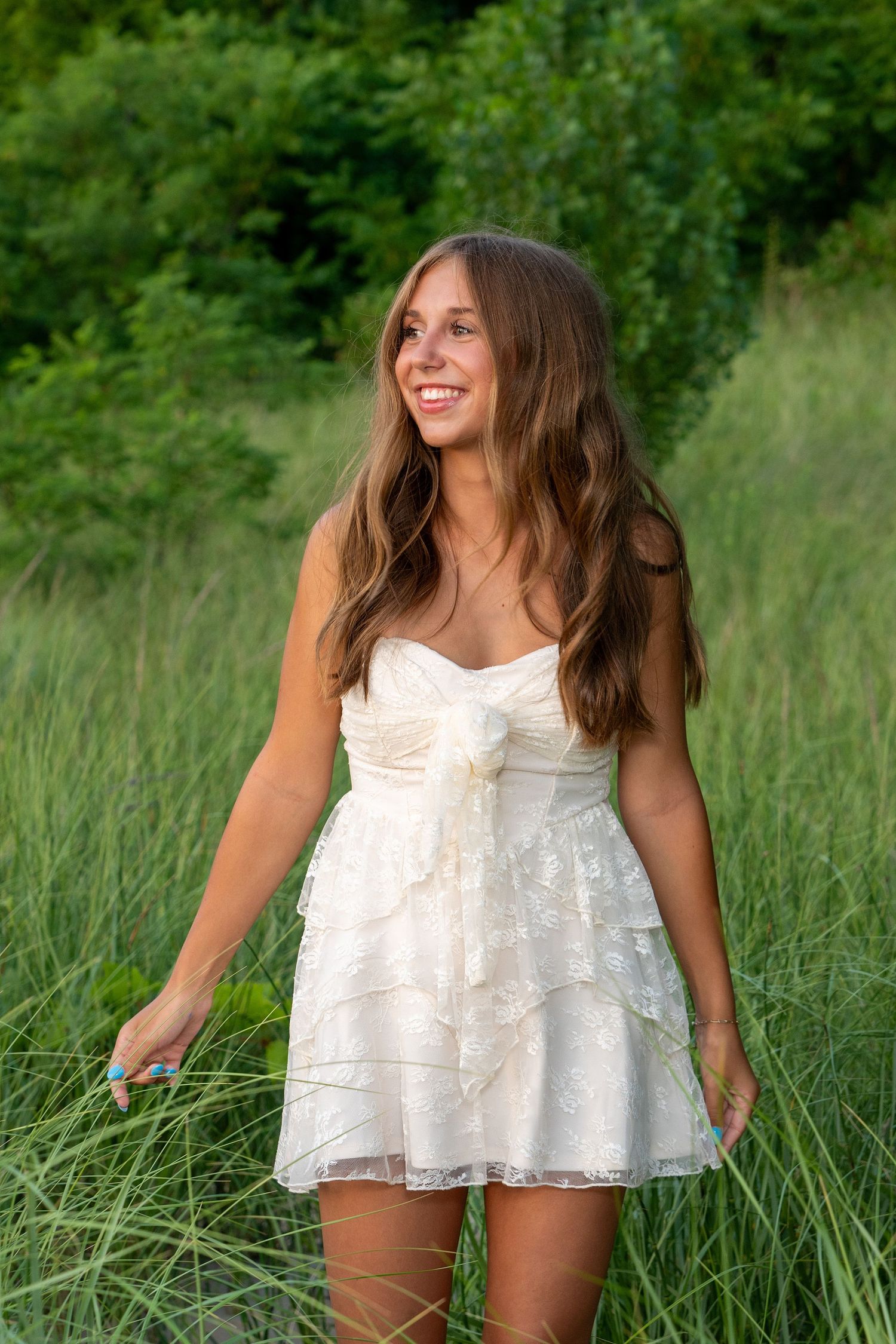 Summer fashion photography featuring a white lace top in a grassy field.