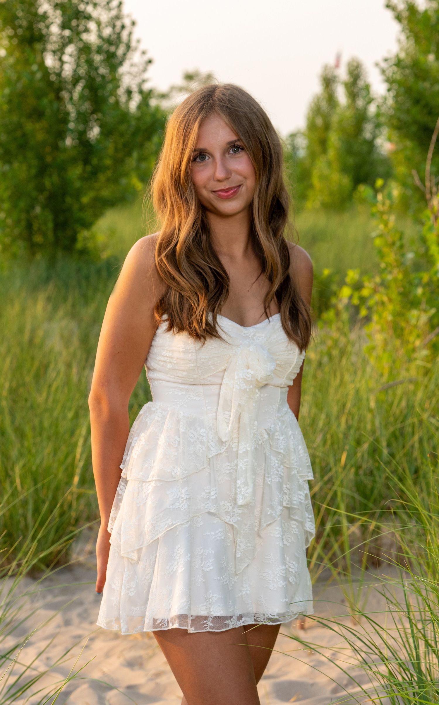 Beach-inspired fashion shoot with a flowing white lace top against natural greenery.