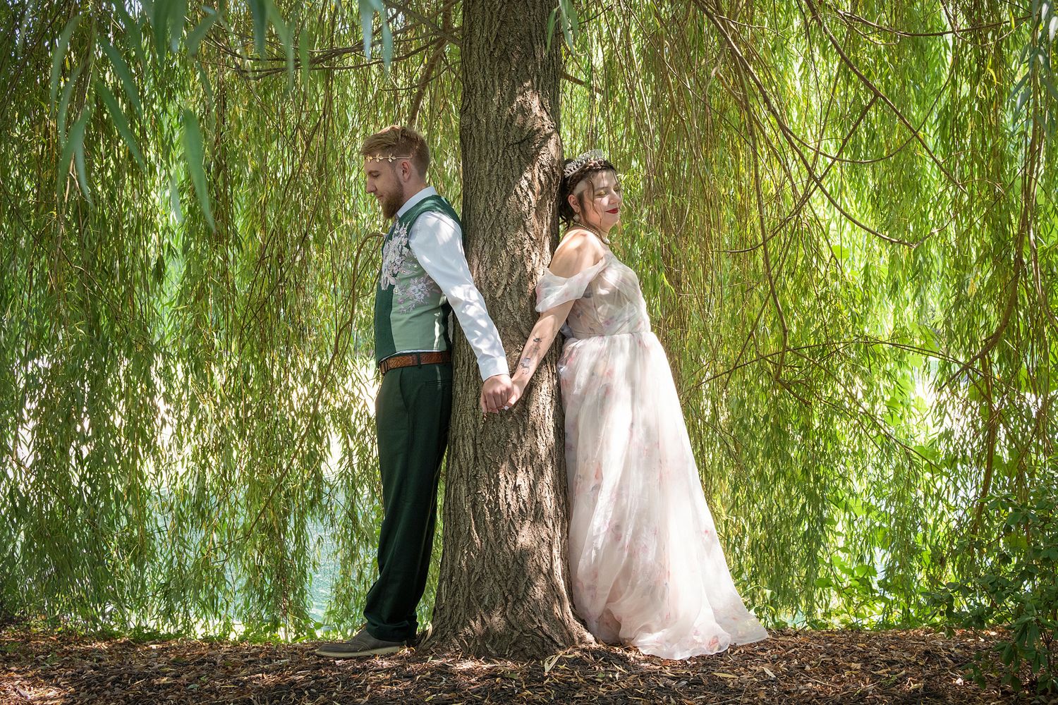 Romantic wedding photos taken under a weeping willow tree with soft natural lighting.