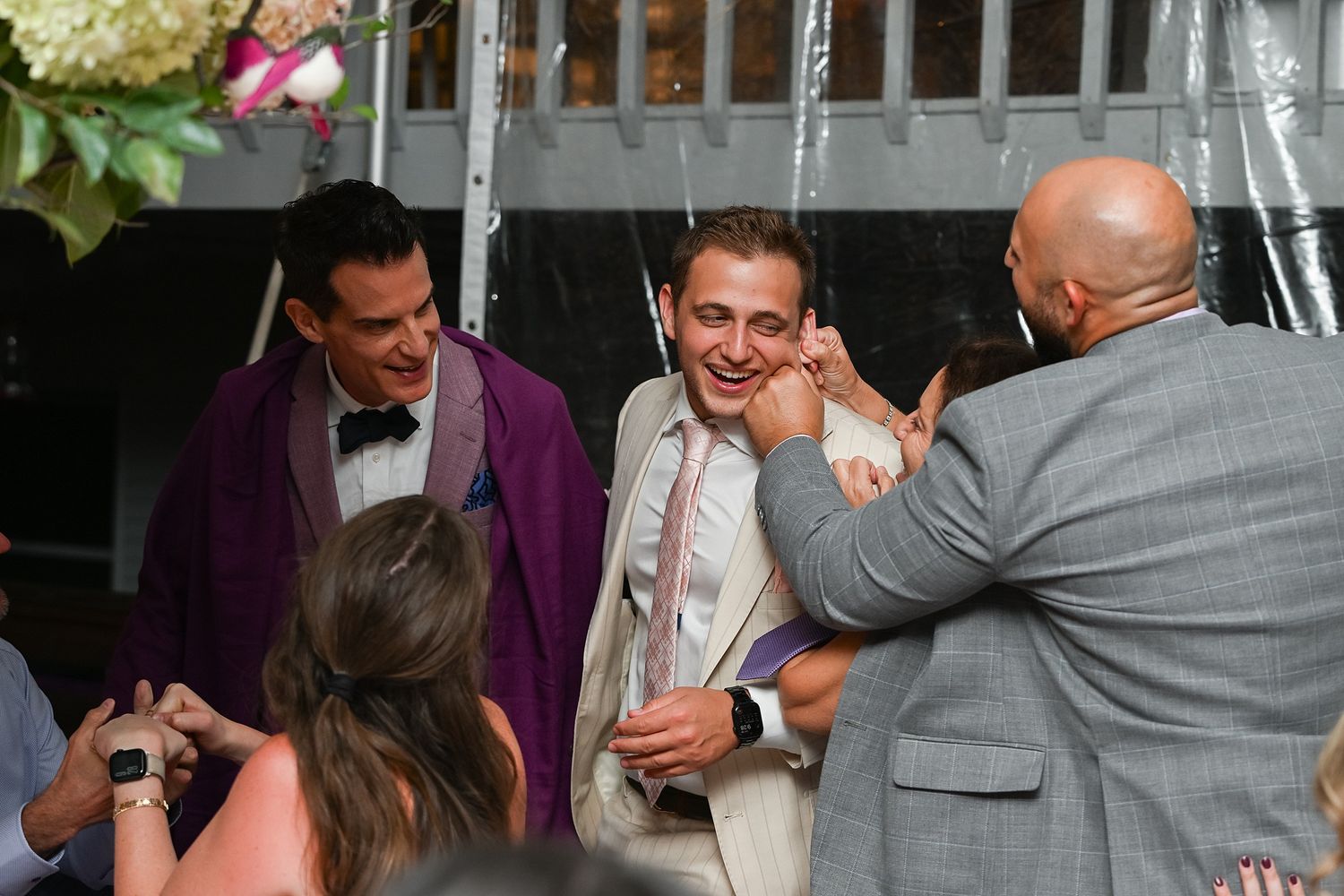 Wedding guests laughing and socializing during a reception celebration.