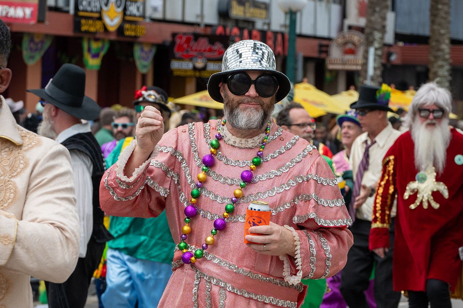 Parade participants in elaborate costumes and decorative outfits performing for the crowd.