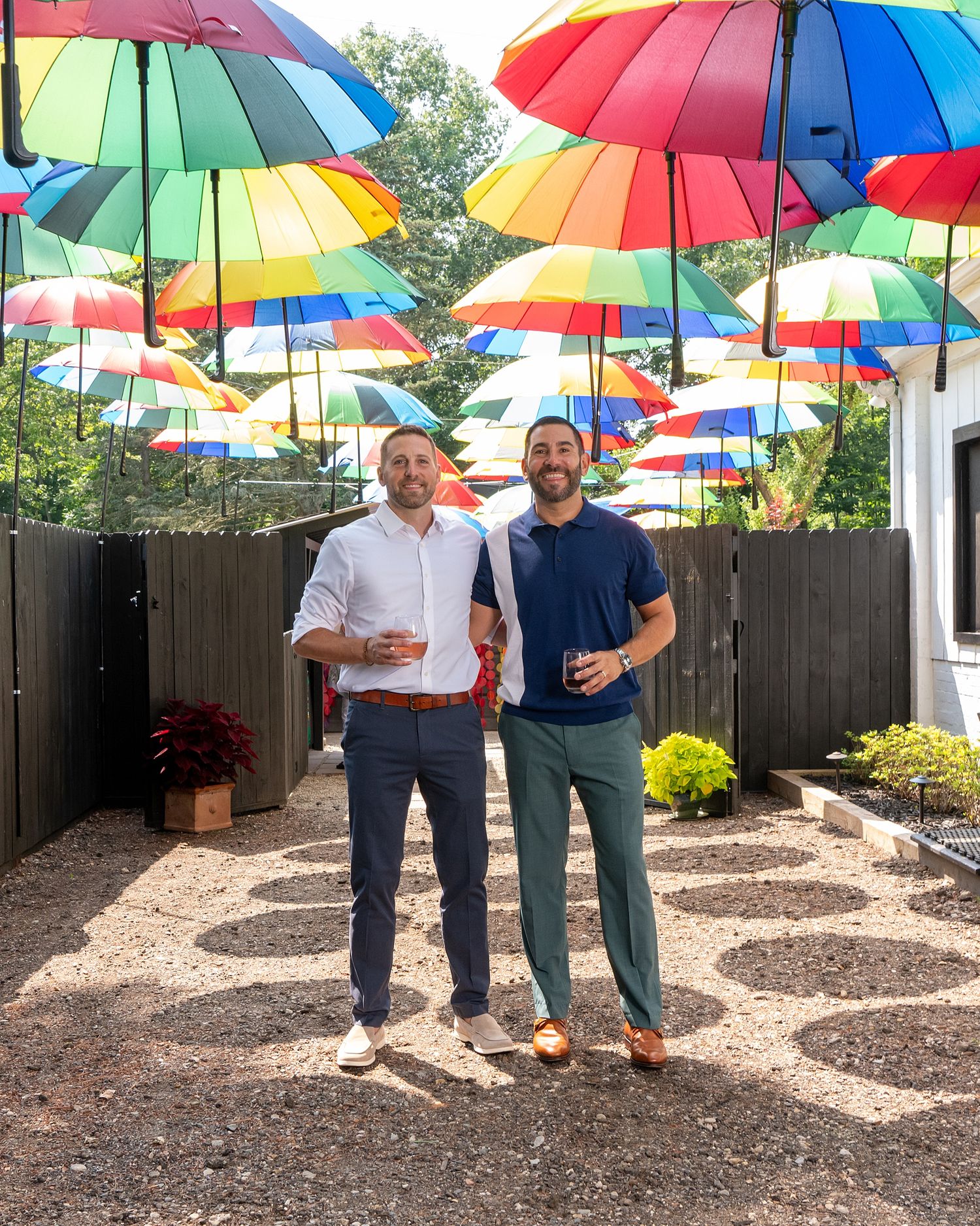 Colorful rainbow umbrellas create a vibrant canopy over a backyard garden space.