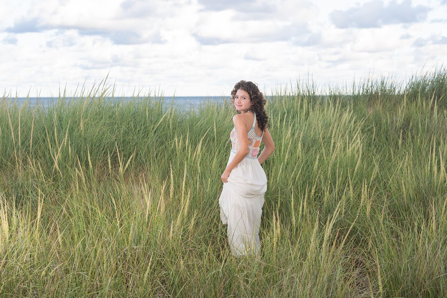 Coastal landscape with figure in white dress among beach grass.