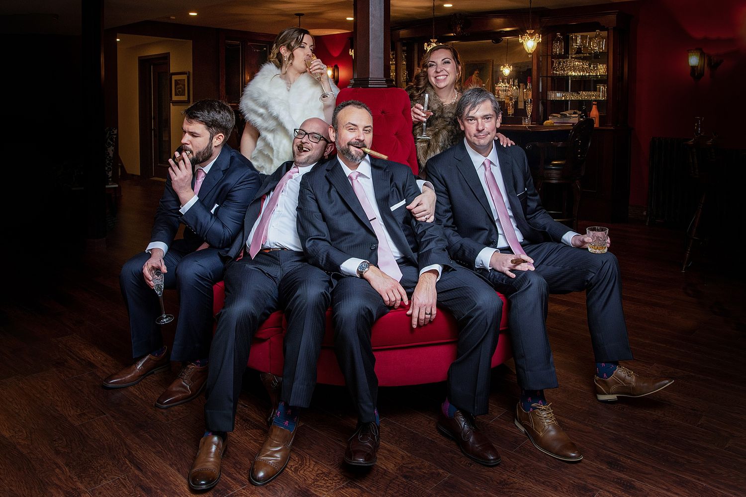 Group seated on red couches in dimly lit room.