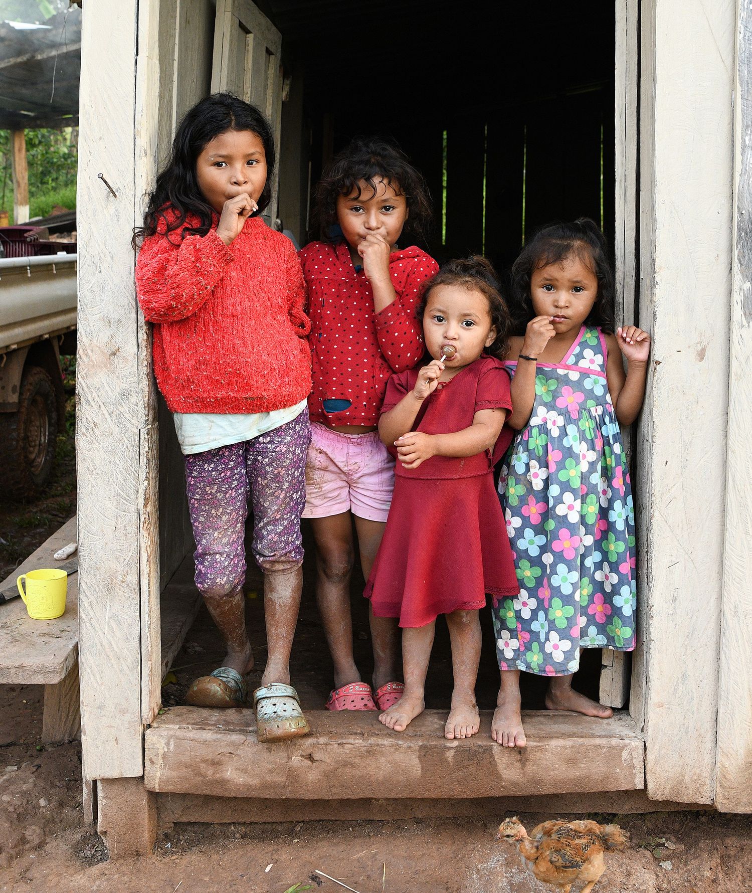 A series of photos showing small children sitting together in a wooden doorway.