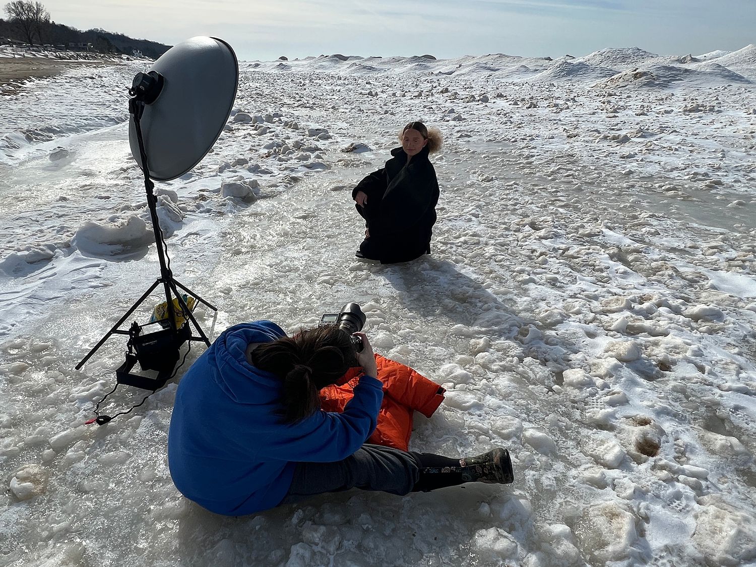 Photography crew working on snowy terrain with lighting equipment setup.