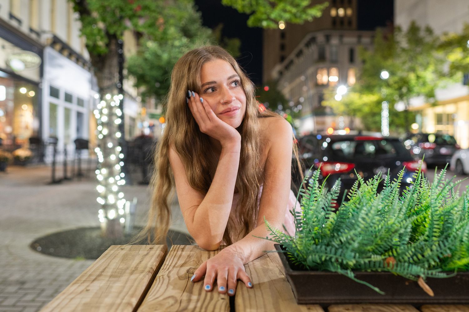 Outdoor cafe seating area with greenery and ambient evening lighting.