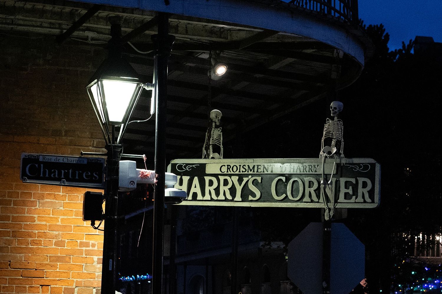 Illuminated vintage sign for Larry's Corner against brick wall at night.