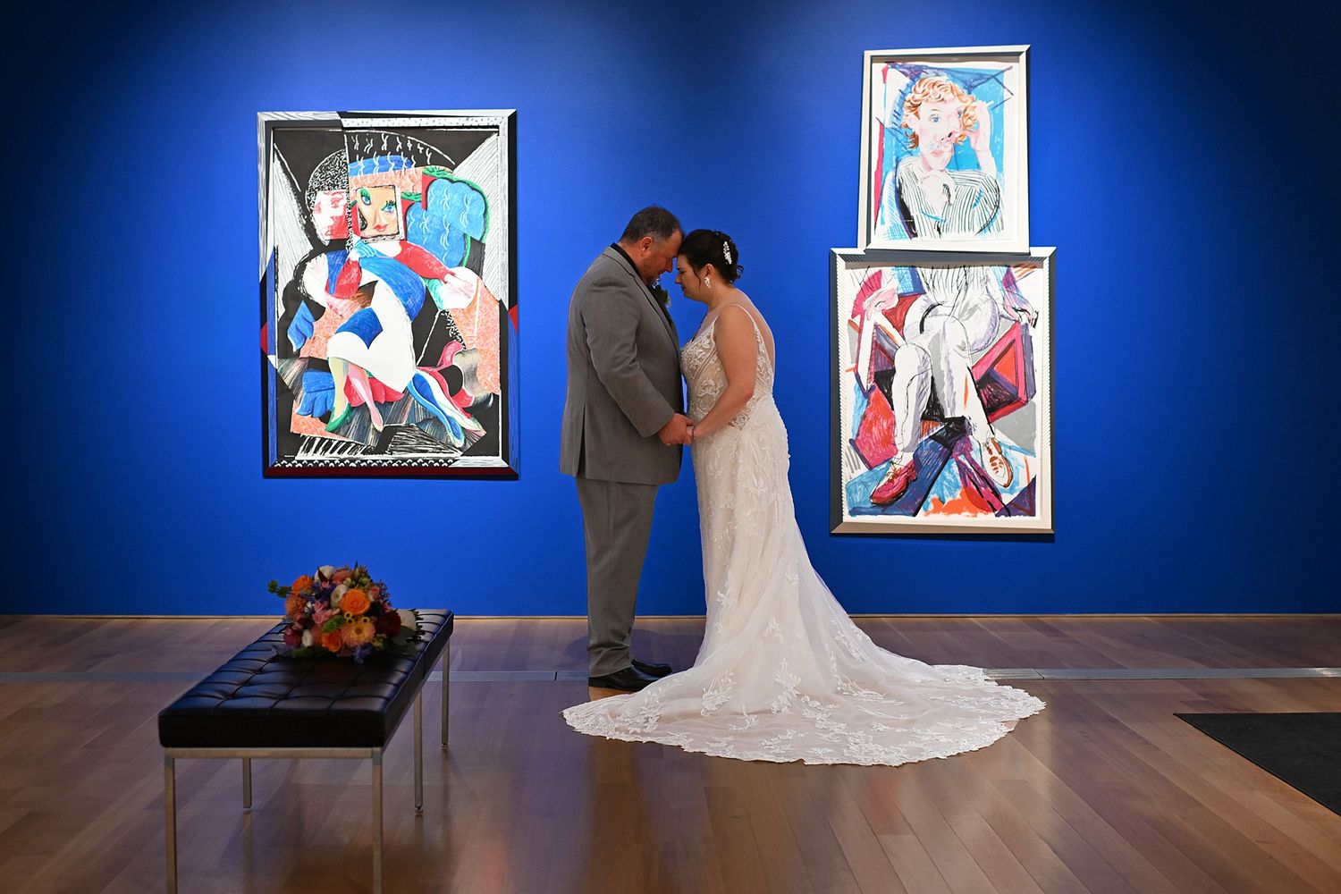 Wedding photoshoot in an art gallery with vibrant blue walls and colorful artwork.