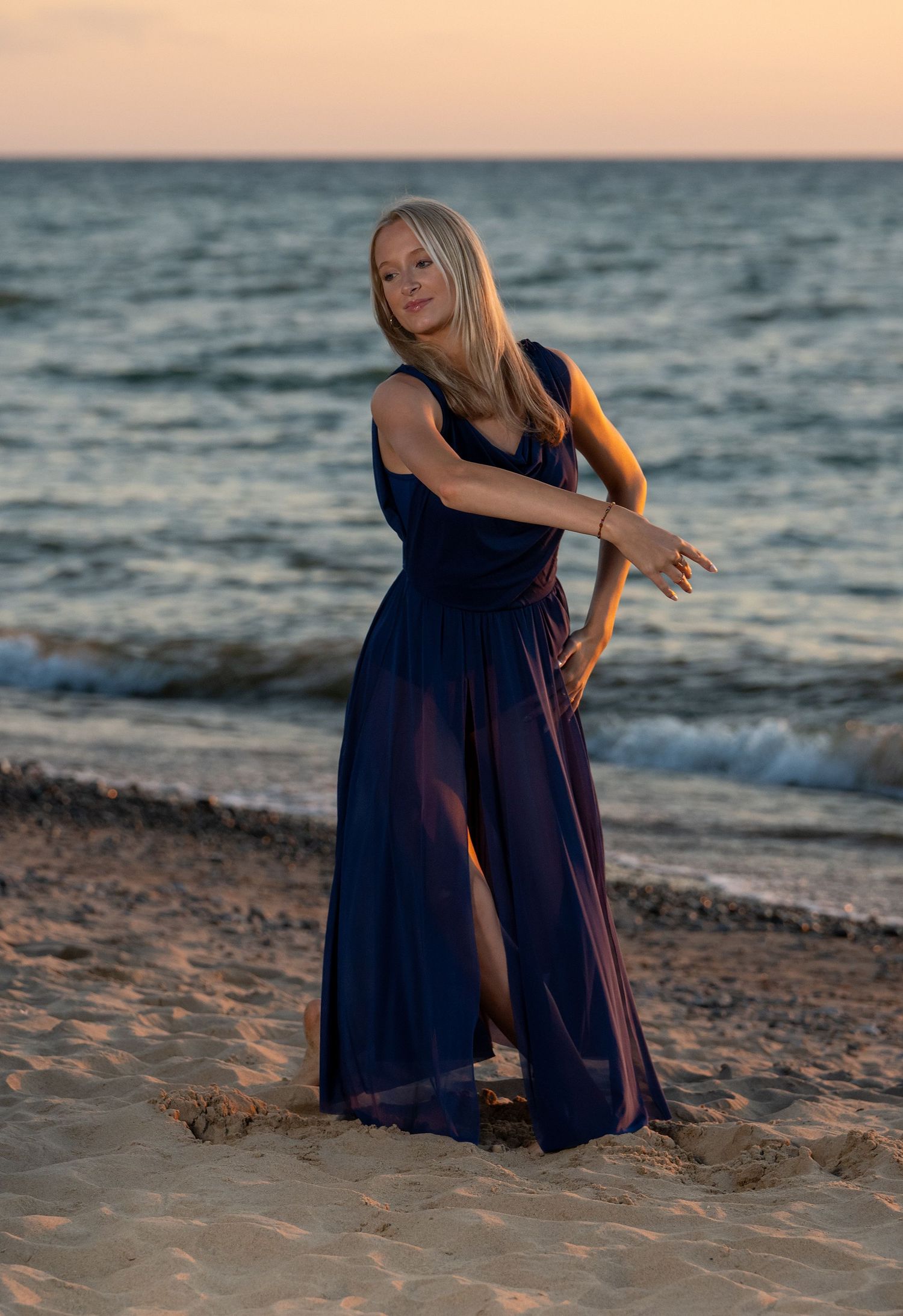 Sunset beach photoshoot featuring dark dress and golden evening light on sandy shore.