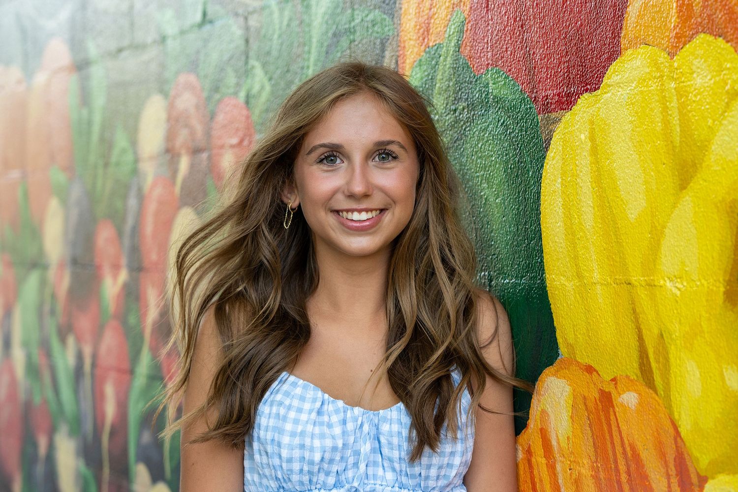 Portrait against vibrant street art mural with colorful geometric patterns.