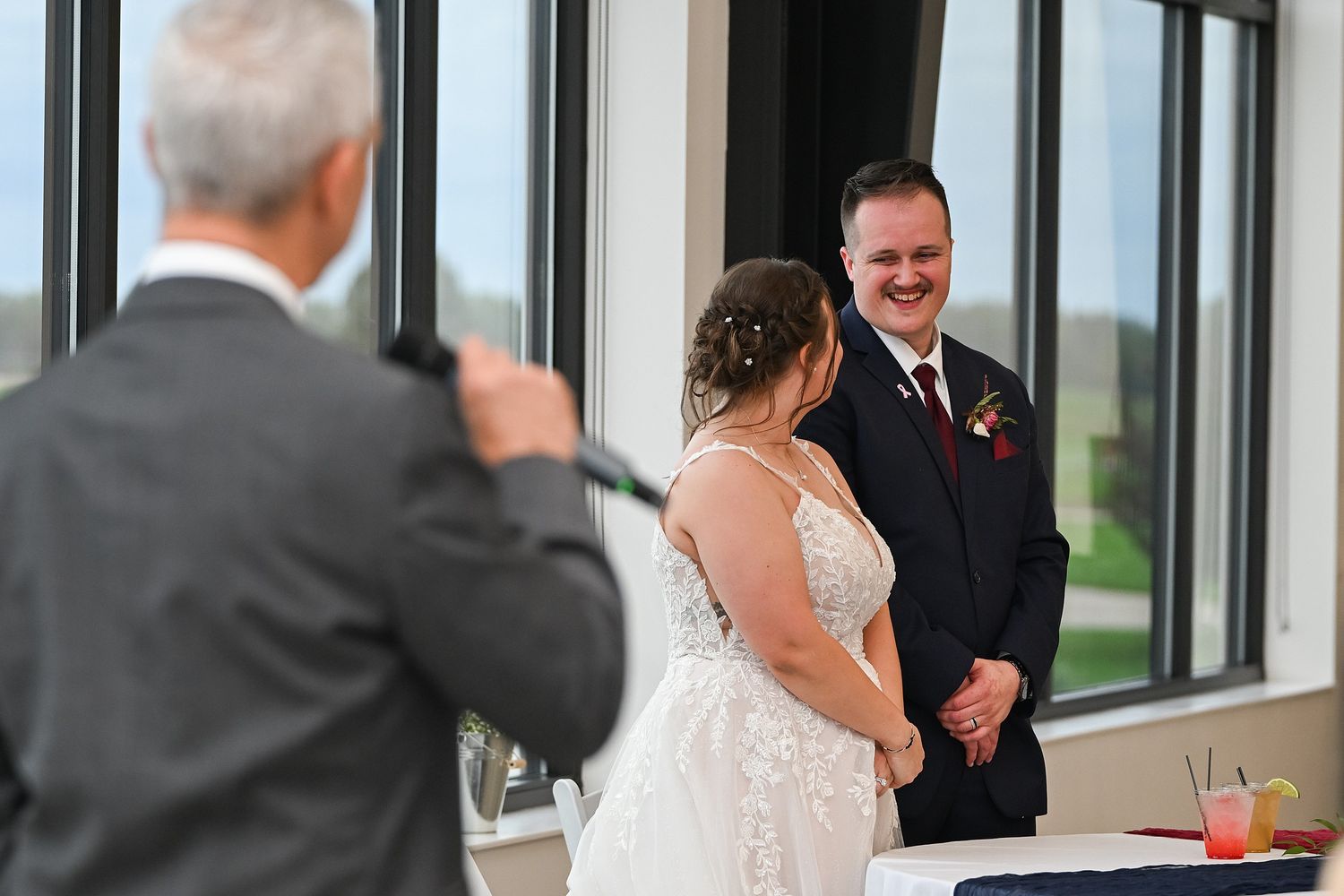 Bride and groom share a joyful moment during wedding reception speech.