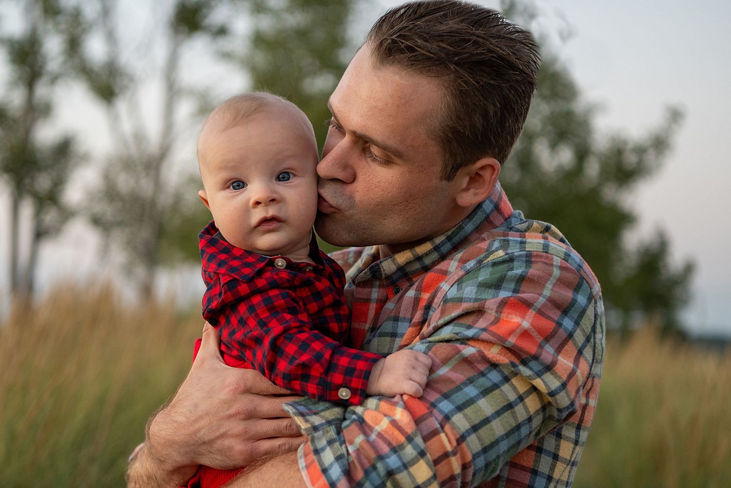Parent and child in matching plaid and buffalo check outfits sharing tender moment.