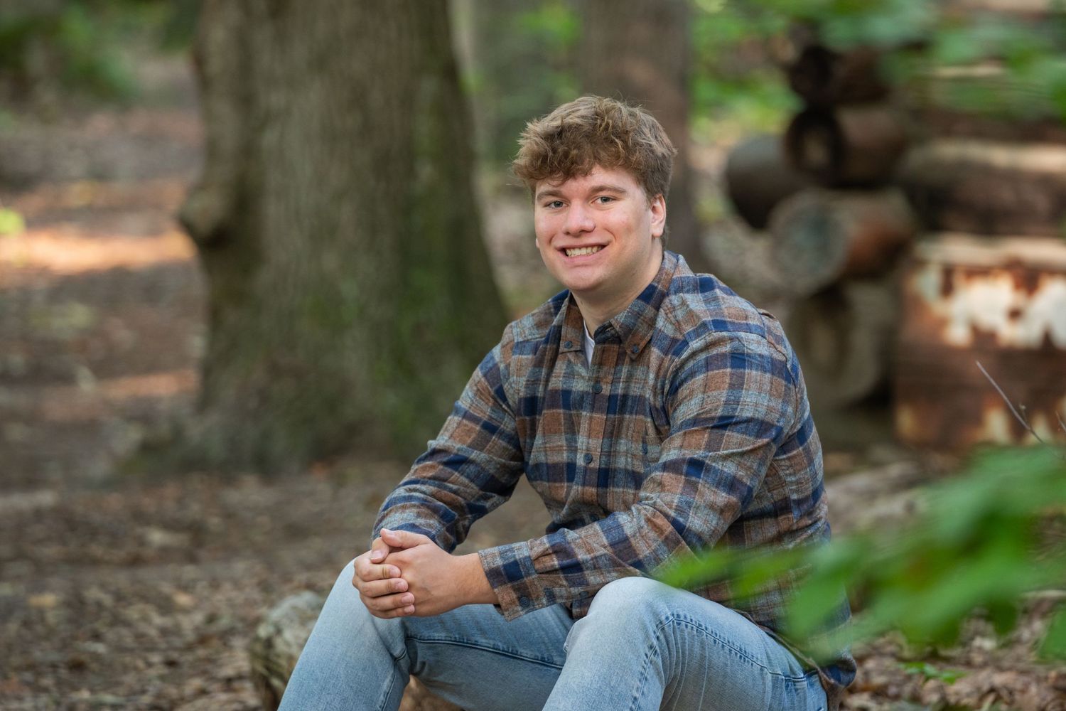 Outdoor portrait in wooded setting with natural lighting and rustic casual style.